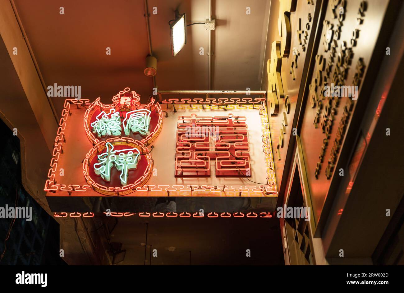 Regardant vers le haut d'un panneau publicitaire de néon de magasin de pion la nuit au coin de la rue de Wan Chai. Hong Kong - 28 août 2023 Banque D'Images