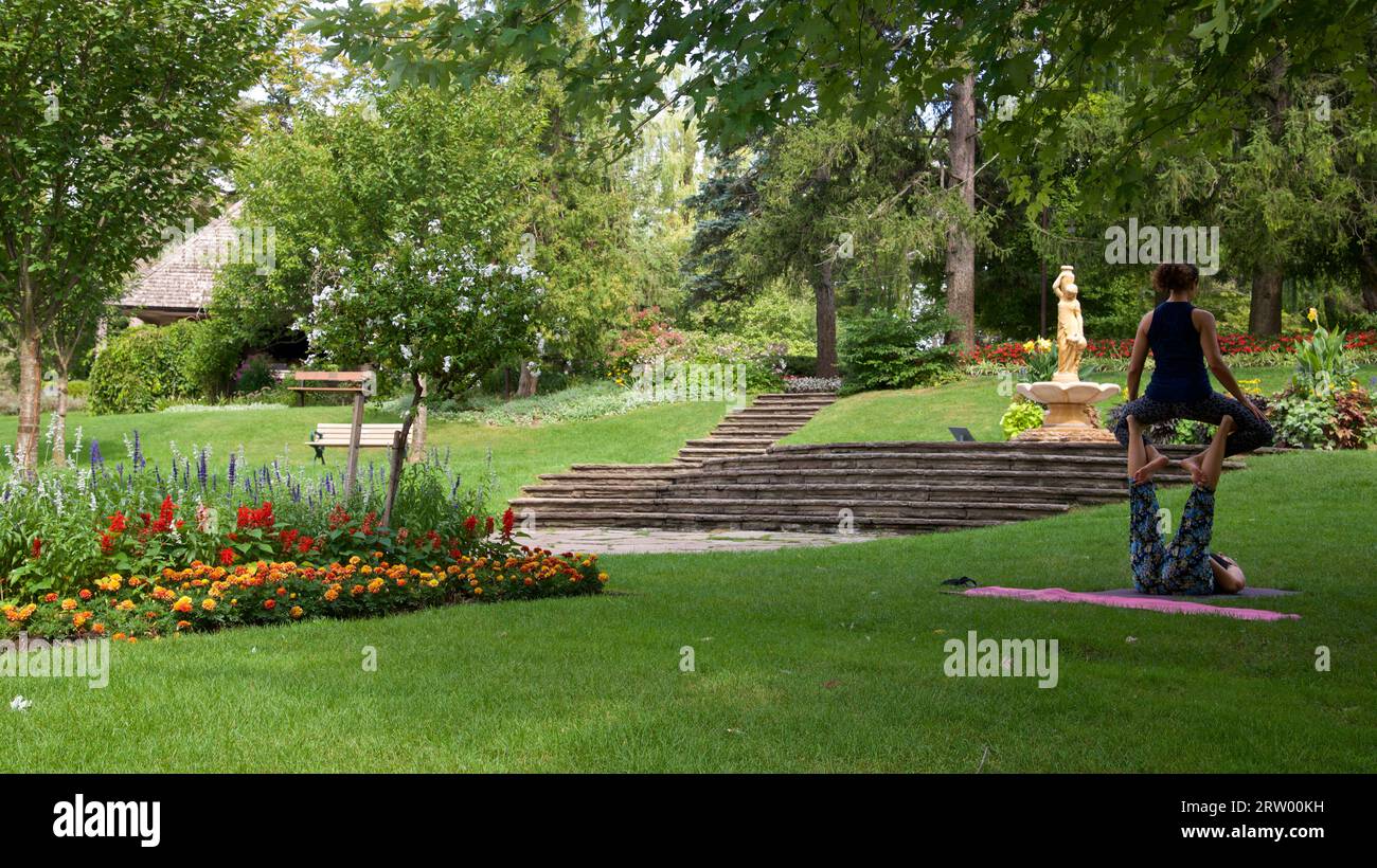 Jeunes femmes faisant du yoga en plein air. Fond d'un beau parc public en été Banque D'Images