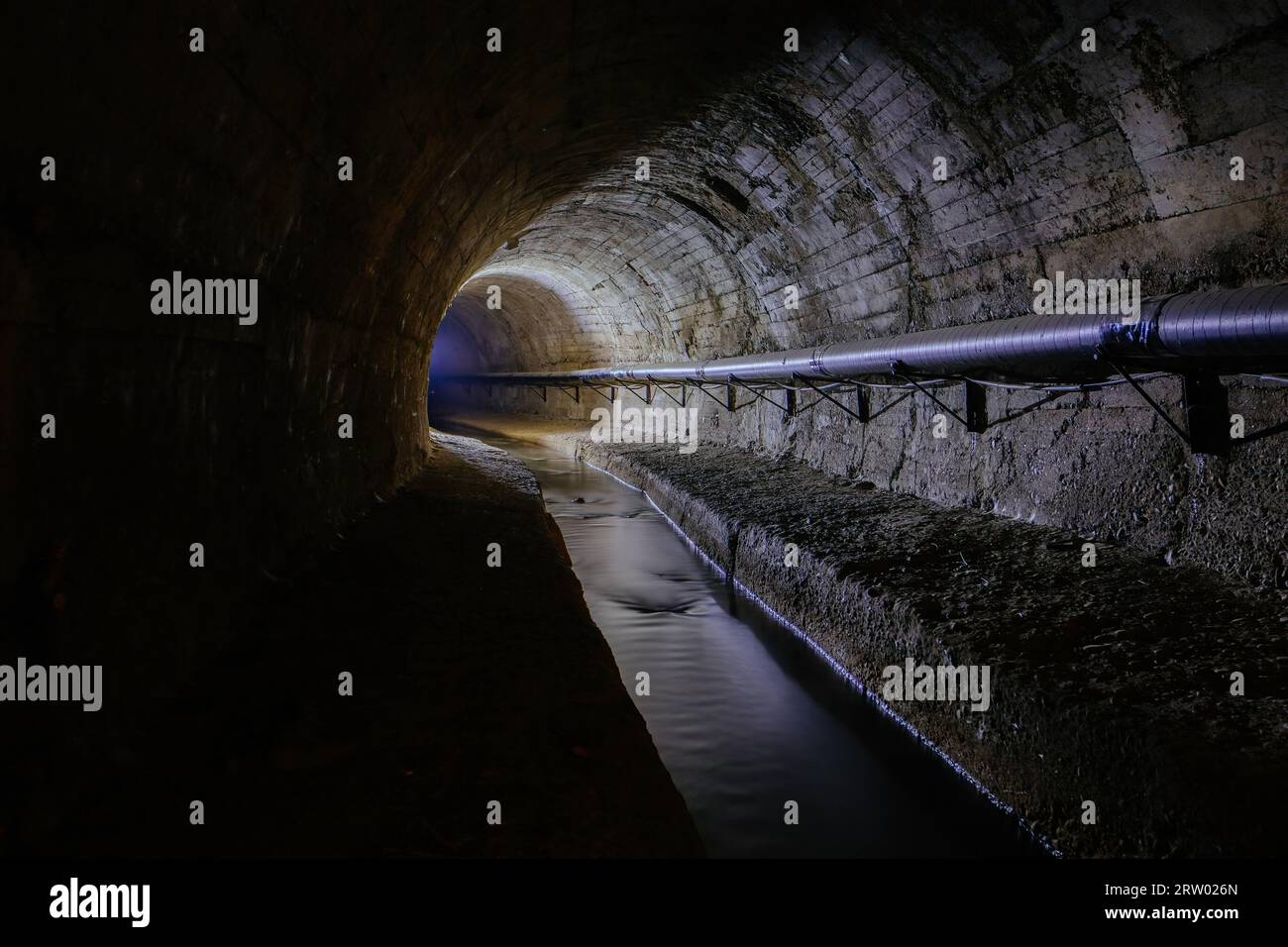 Tunnel souterrain d'égout urbain voûté avec eaux usées sales. Banque D'Images