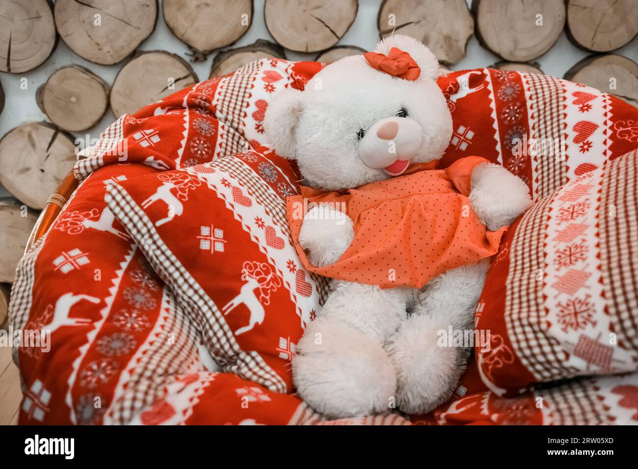 Pelucheux pelucheux doux ours fille dans des oreillers et couverture du nouvel an sur une chaise à bascule. Banque D'Images