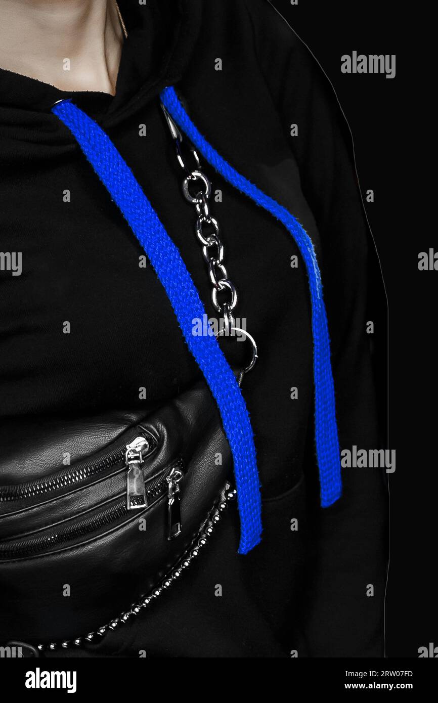 Un vélo noir avec de grands lacets bleus longs, un style féminin de vêtements à la maison et un sac sur un fond sombre. Banque D'Images