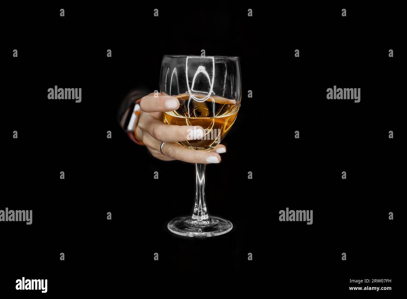 La main d'une femme tient ou tient un verre de boisson alcoolisée de l'obscurité. Banque D'Images