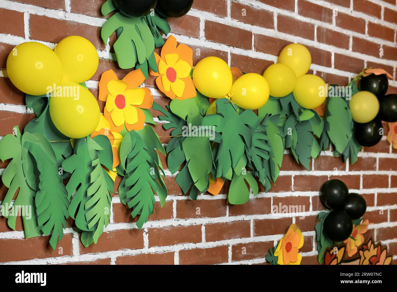 Objets lumineux, décorations sur un mur de briques, intérieur, intérieur dans le style d'une fête hawaïenne, tropiques, jungle. Banque D'Images