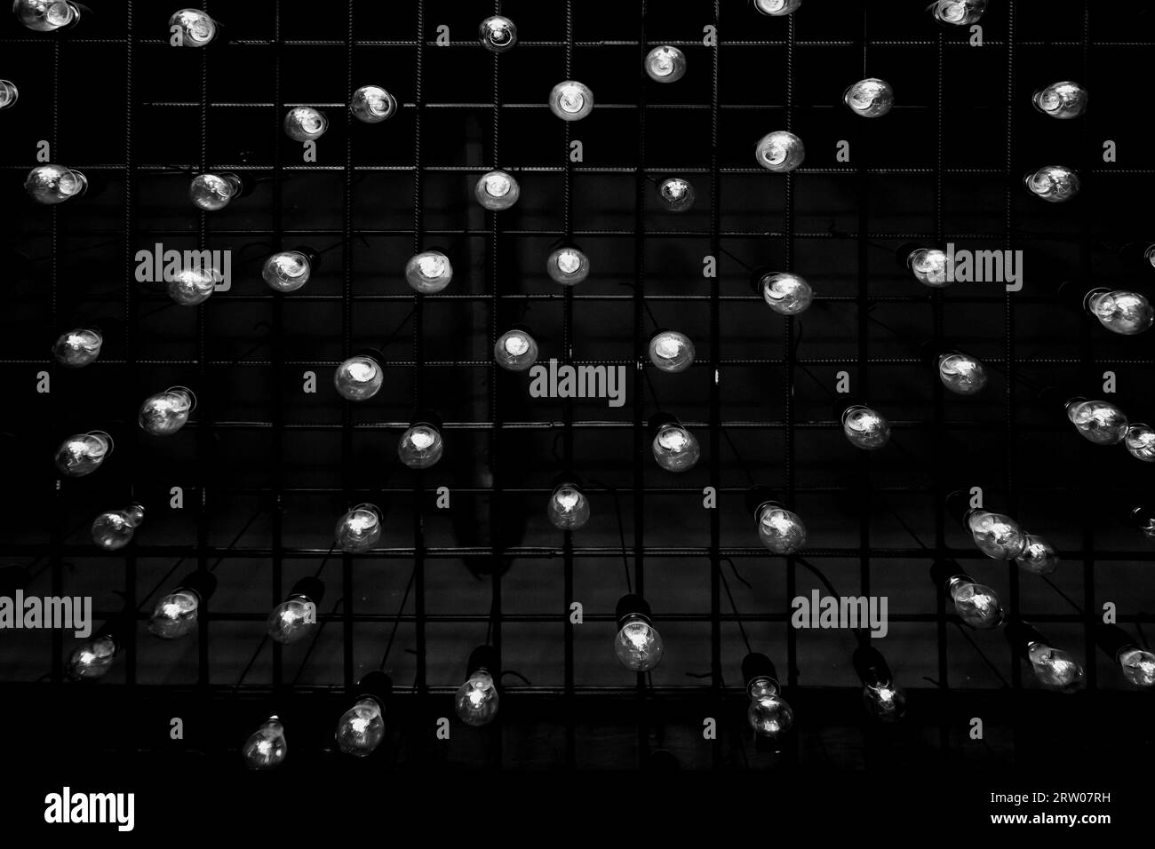 Un groupe de beaucoup d'ampoules blanches élément intérieur de plafond fond sombre abstrait. Banque D'Images
