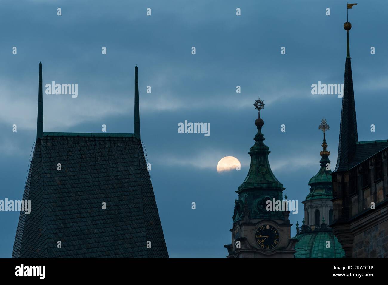 Pont tour du pont Charles à Prague au-dessus de la Vlatva rivière la nuit avec pleine lune dans le ciel derrière les nuages Banque D'Images