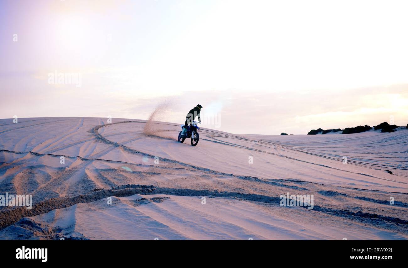 Conduite, poussière de sable ou athlète en moto pour l'aventure, l'action ou la remise en forme dans l'entraînement en plein air au coucher du soleil. Conducteur de terre, désert ou sport sur moto Banque D'Images