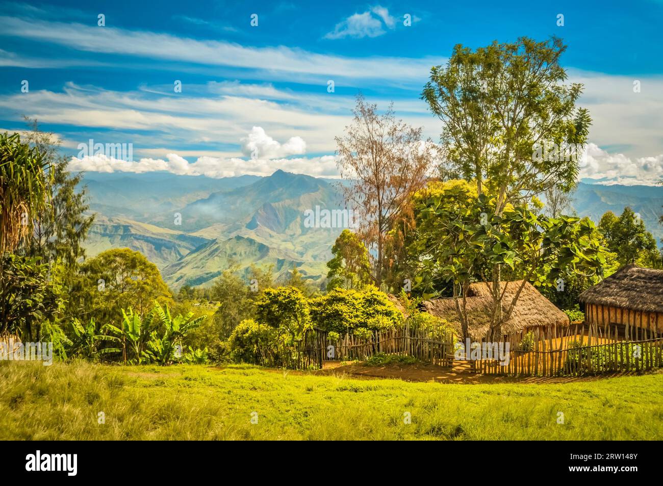 Photo de maison de village avec clôture en bois et de hautes montagnes au loin dans le village de Sara et Mt. Michael en Papouasie-Nouvelle-Guinée Banque D'Images