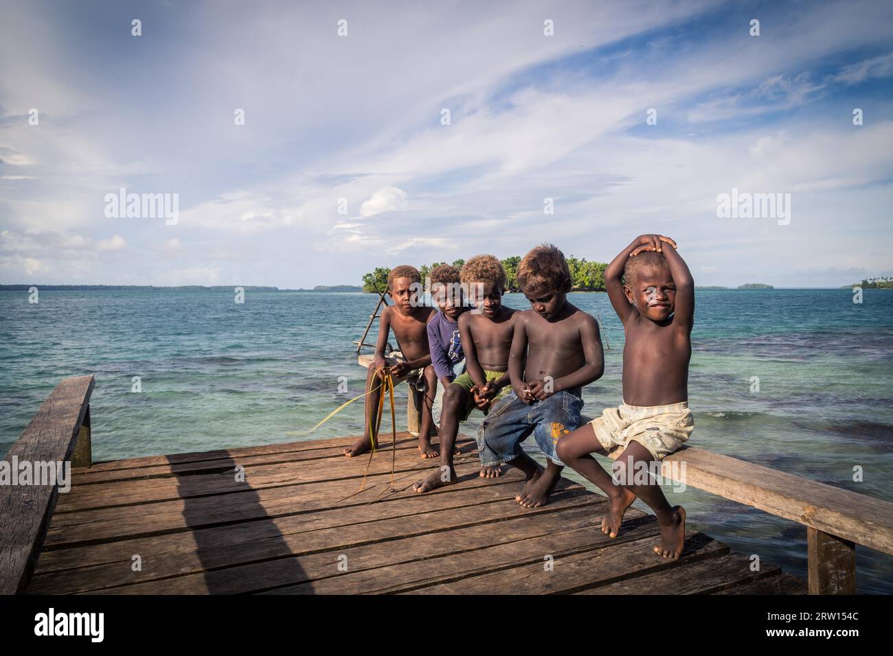 Chea Vilalge, Îles Salomon, 15 juin 2015 : groupe d'enfants assis sur une jetée en bois Banque D'Images