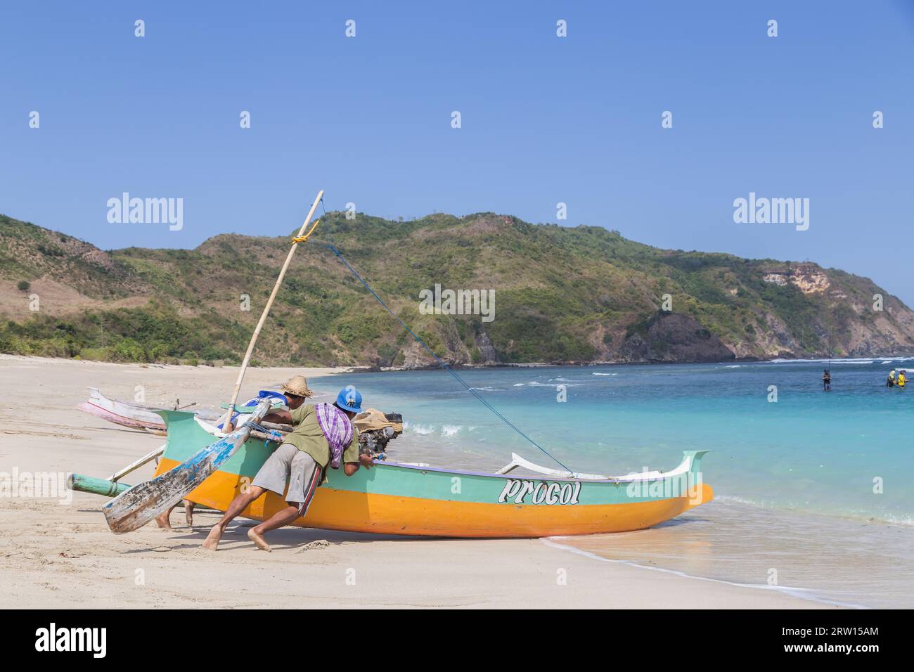 Kuta, Lombok, Indonésie, 16 juillet 2015 : deux pêcheurs sur la plage poussent un bateau de pêche dans l’océan pour aller pêcher Banque D'Images