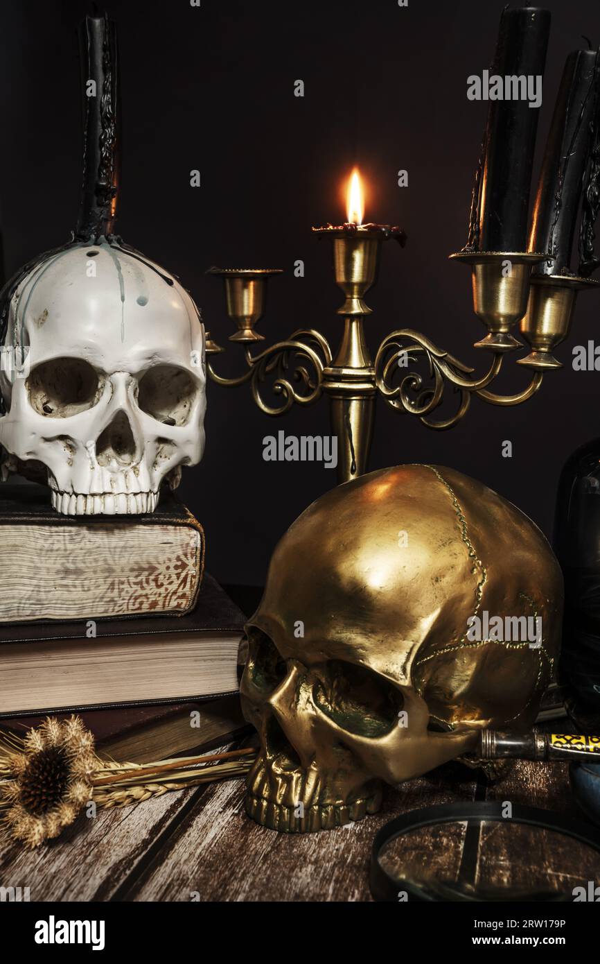 Une image de bougies dans un chandelier, un crâne avec des gouttes de cère, un autre or et une bougie allumée Banque D'Images