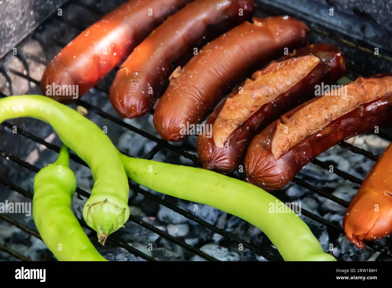 Barbecue au charbon barbecue Grill dans l'arrière-cour de Country Side, préparer, griller des saucisses et des poivrons verts sur le gril avec clôture en bois en arrière-plan Banque D'Images