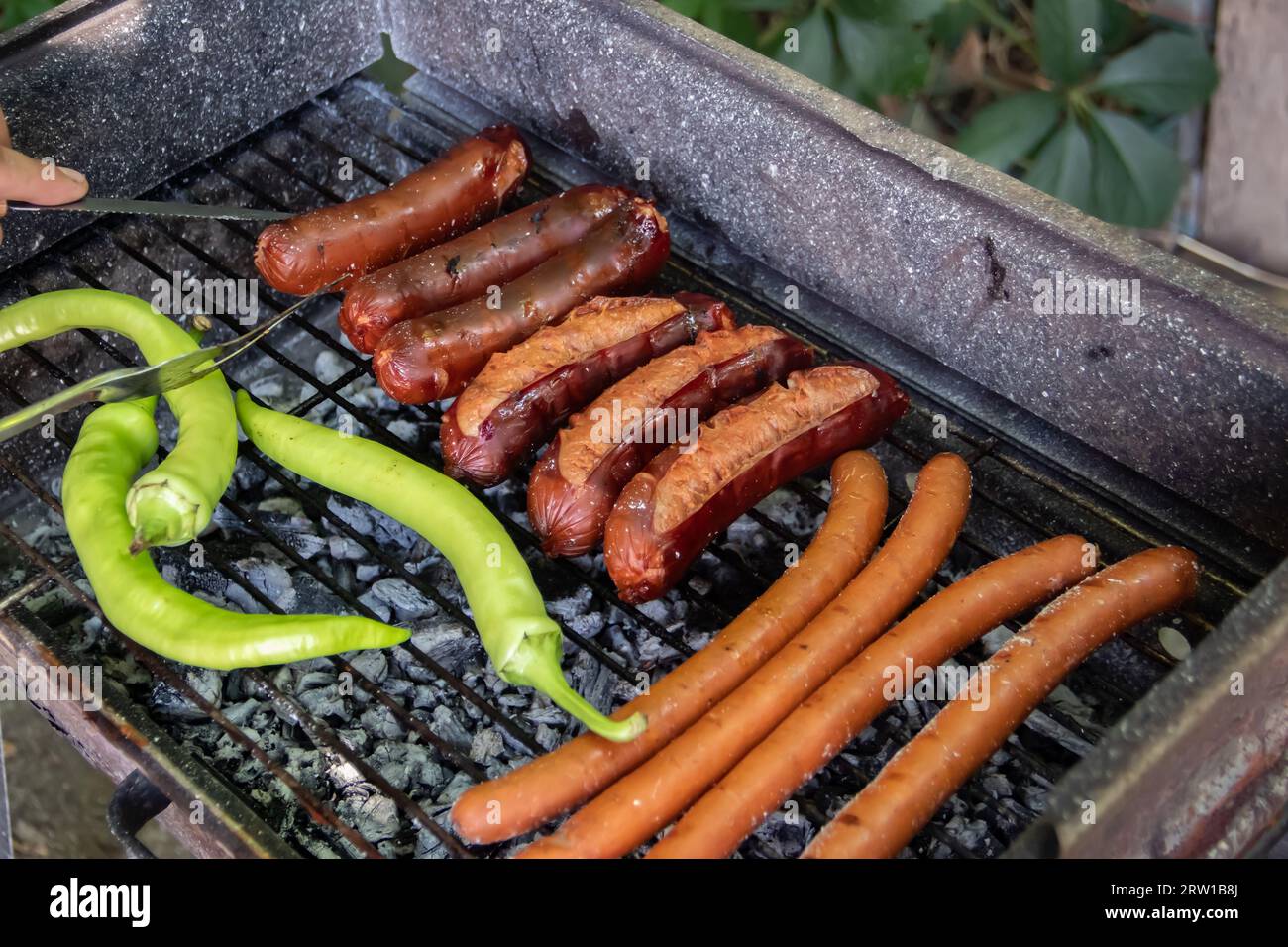 Barbecue au charbon barbecue Grill dans l'arrière-cour de Country Side, préparer, griller des saucisses et des poivrons verts sur le gril avec clôture en bois en arrière-plan Banque D'Images