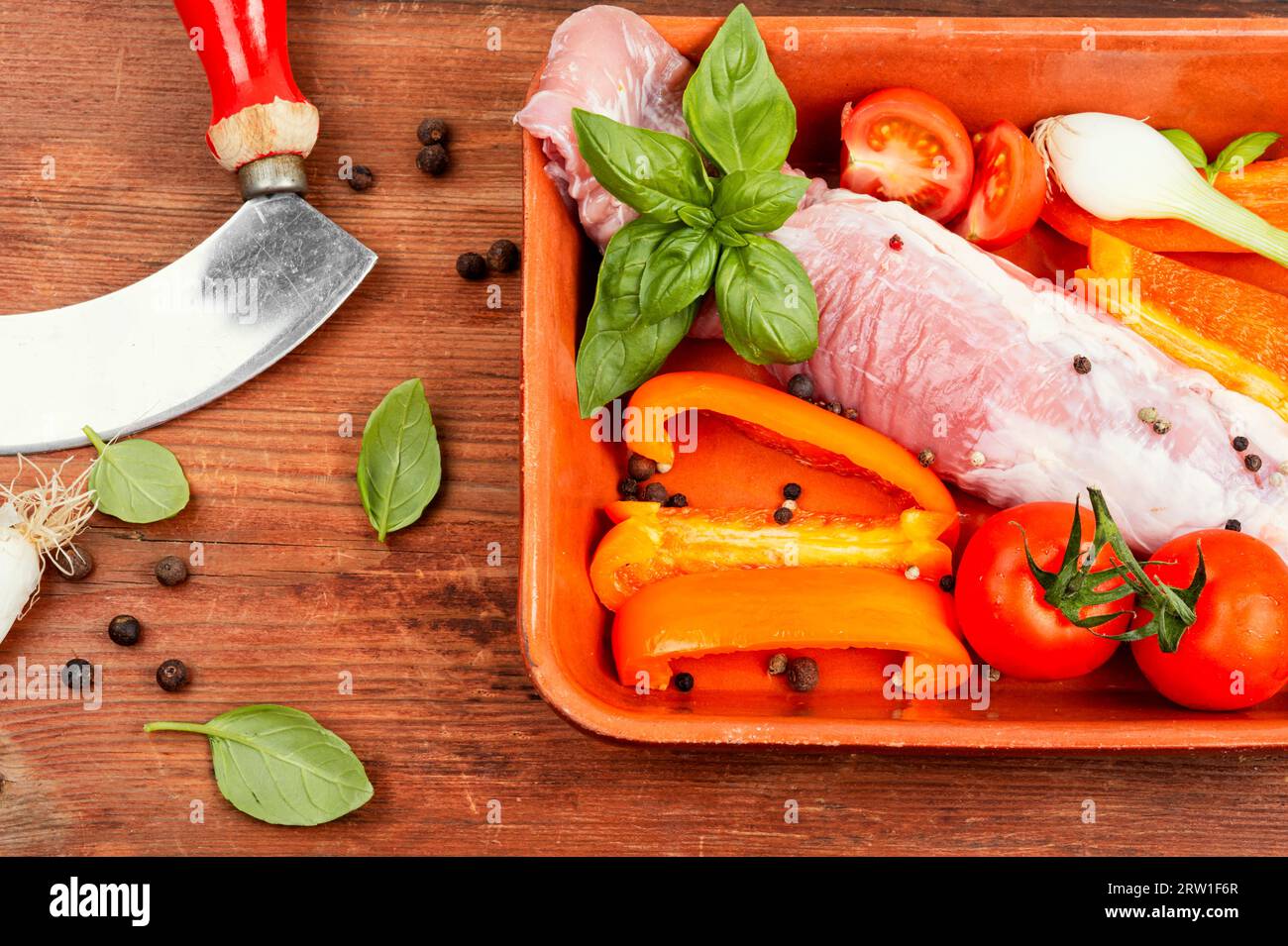 Filet de porc frais avec des légumes dans un plat allant au four sur fond en bois. Banque D'Images