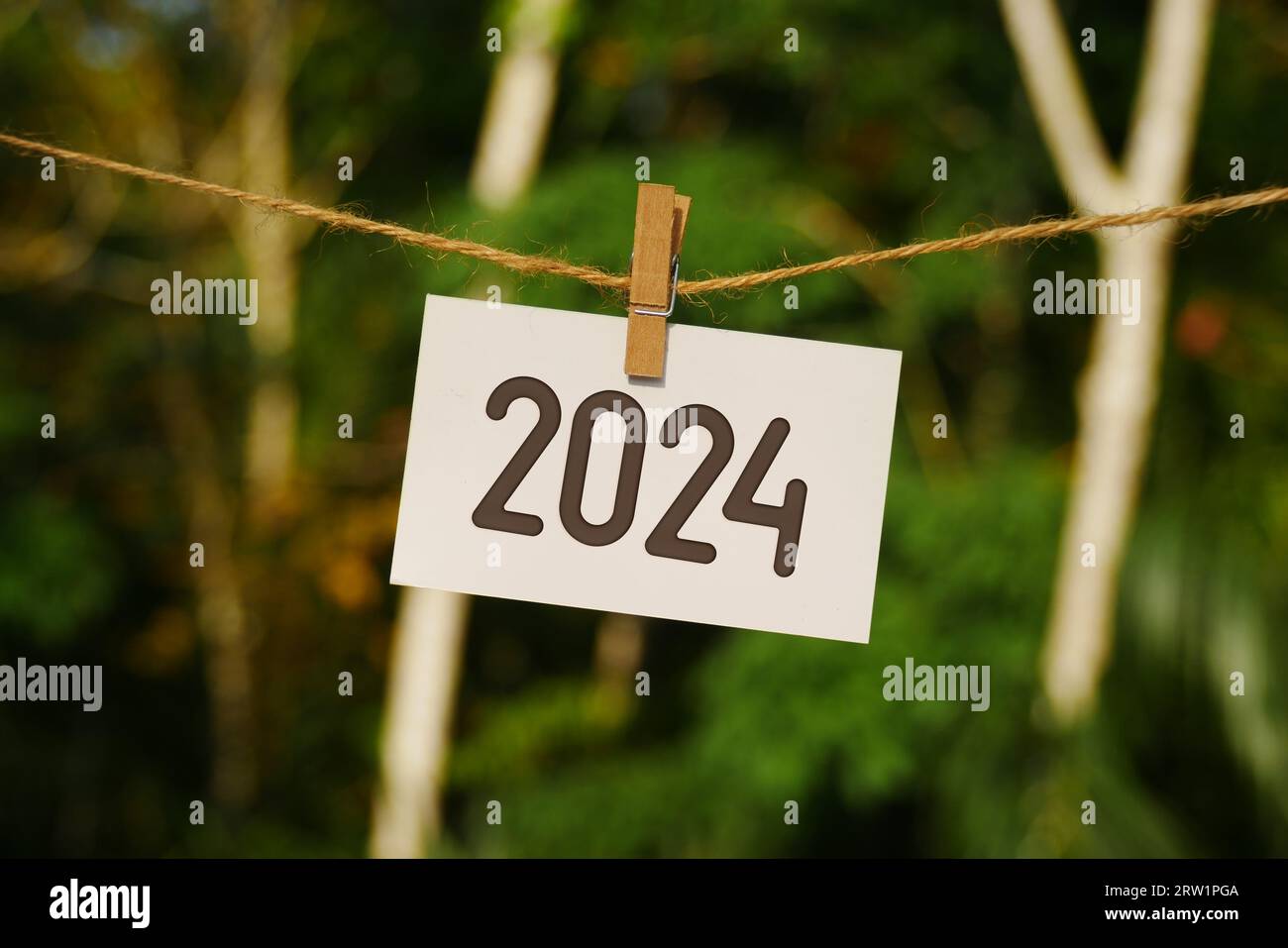 2024 sur papier accroché à la corde de jute. Goodbye 2023 bonjour Happy New Year 2024 concept. Banque D'Images