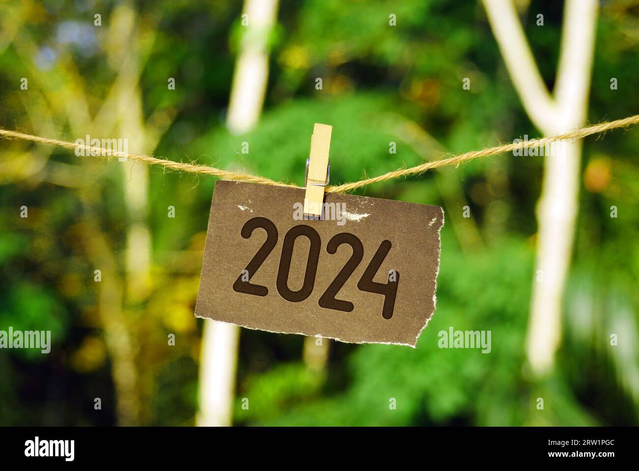 2024 sur papier accroché à la corde de jute. Goodbye 2023 bonjour Happy New Year 2024 concept. Banque D'Images