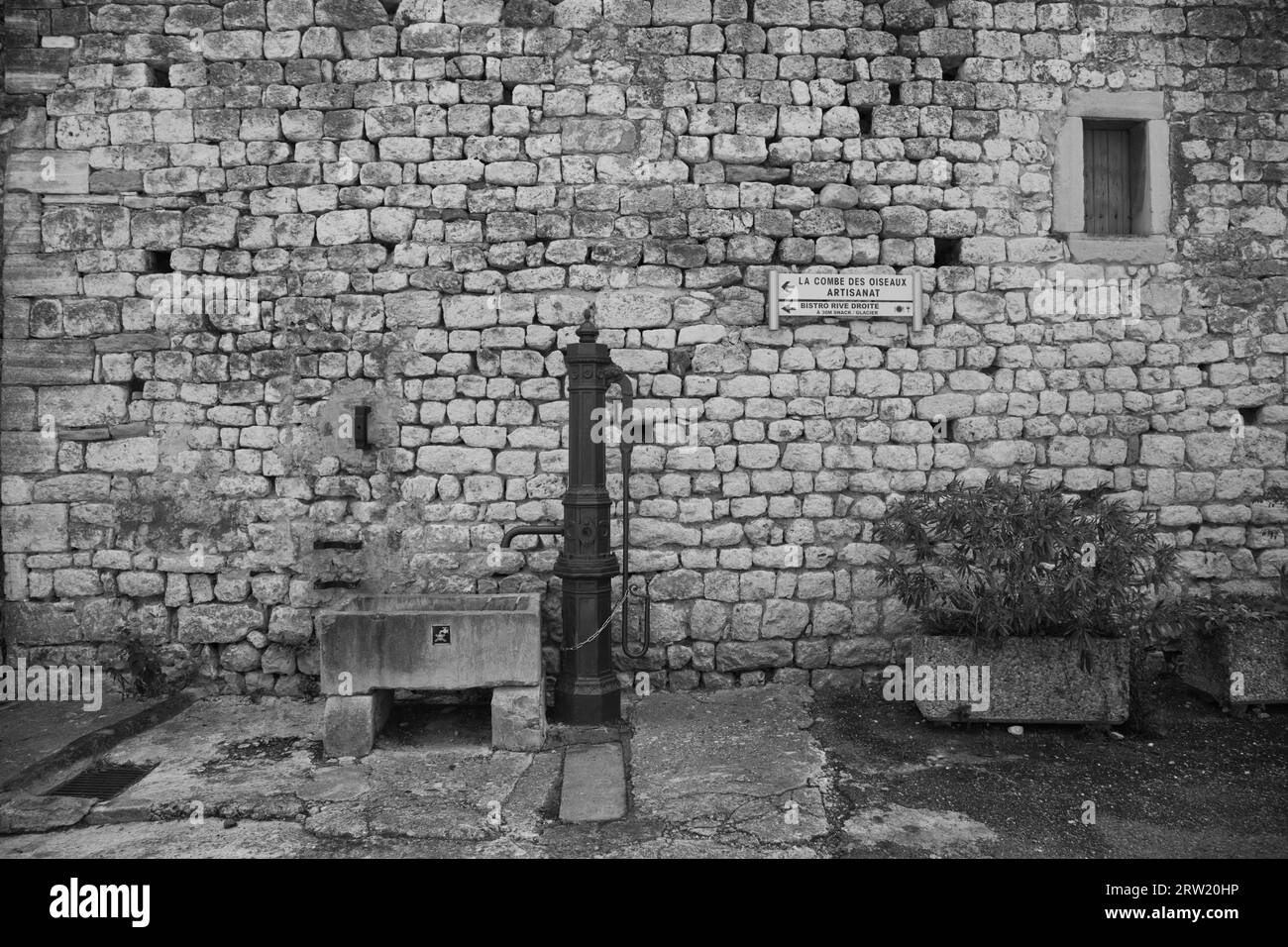 une ancienne fontaine devant un mur de pierre, noir et blanc Banque D'Images