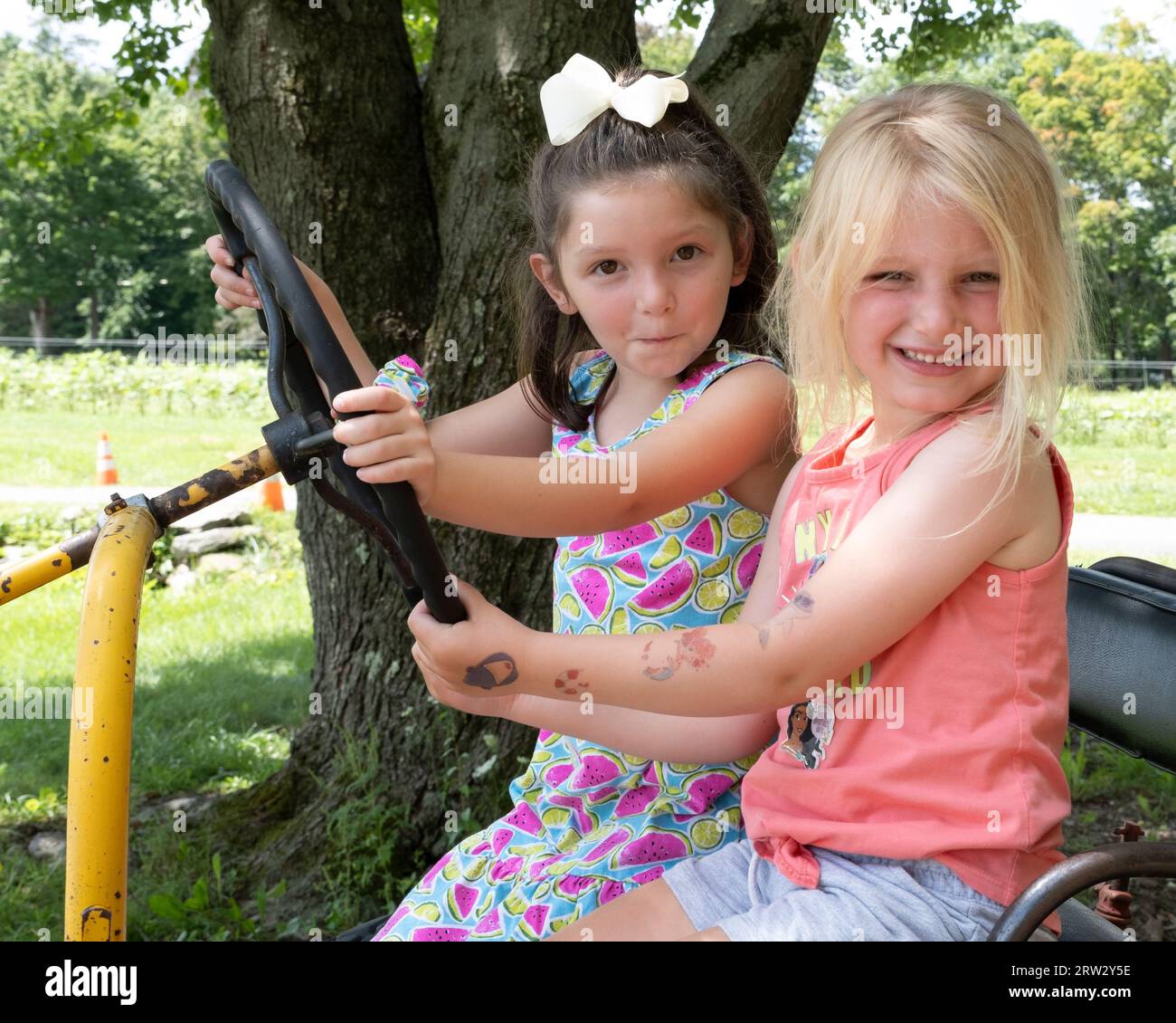 Deux filles s'amusant assis sur un tracteur de ferme Banque D'Images