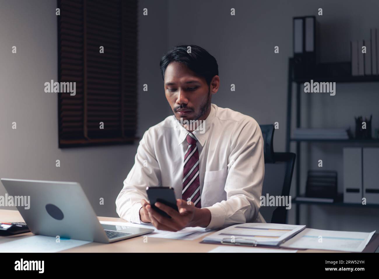 Homme d'affaires utilisant smartphone pour vérifier le rapport tout en analysant les finances et la comptabilité du projet. Banque D'Images