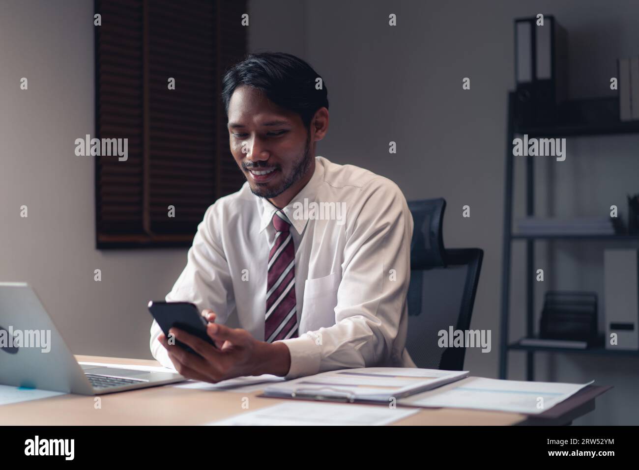 Homme d'affaires utilisant smartphone pour vérifier le rapport tout en analysant les finances et la comptabilité du projet. Banque D'Images