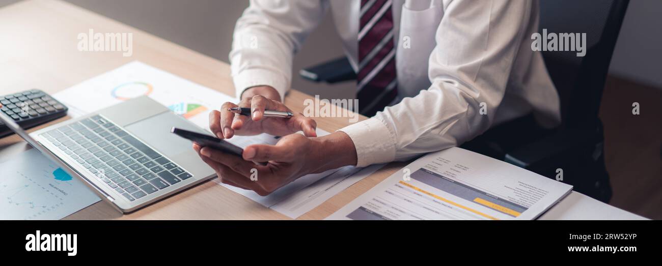Gros plan mains de l'homme d'affaires utilisent smartphone pour vérifier le rapport tout en analysant les finances du projet. Banque D'Images