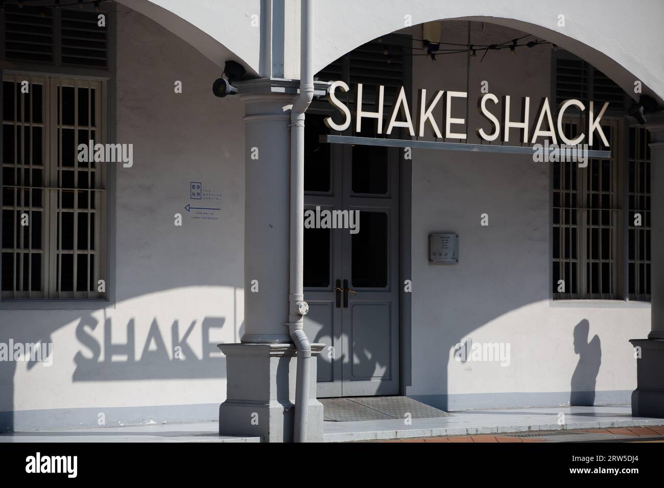 Secouez la signalétique de l'établissement Shack. L'éclairage de l'après-midi donne à la marque une ombre portée intéressante sur le fond blanc. Singapour. Banque D'Images