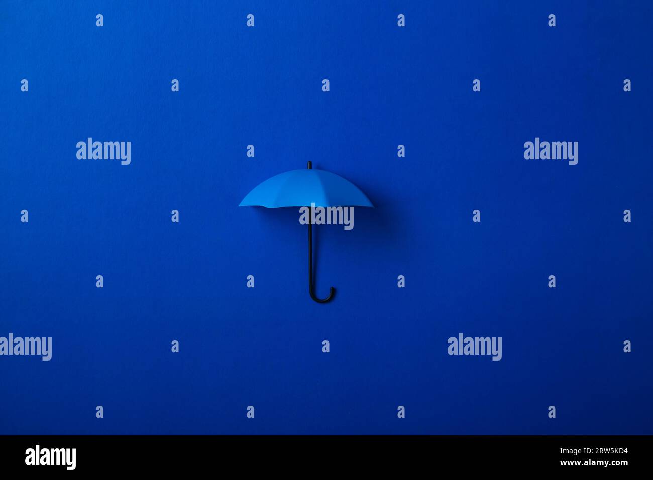 Parapluie bleu unique offrant une protection contre un fond bleu foncé Banque D'Images