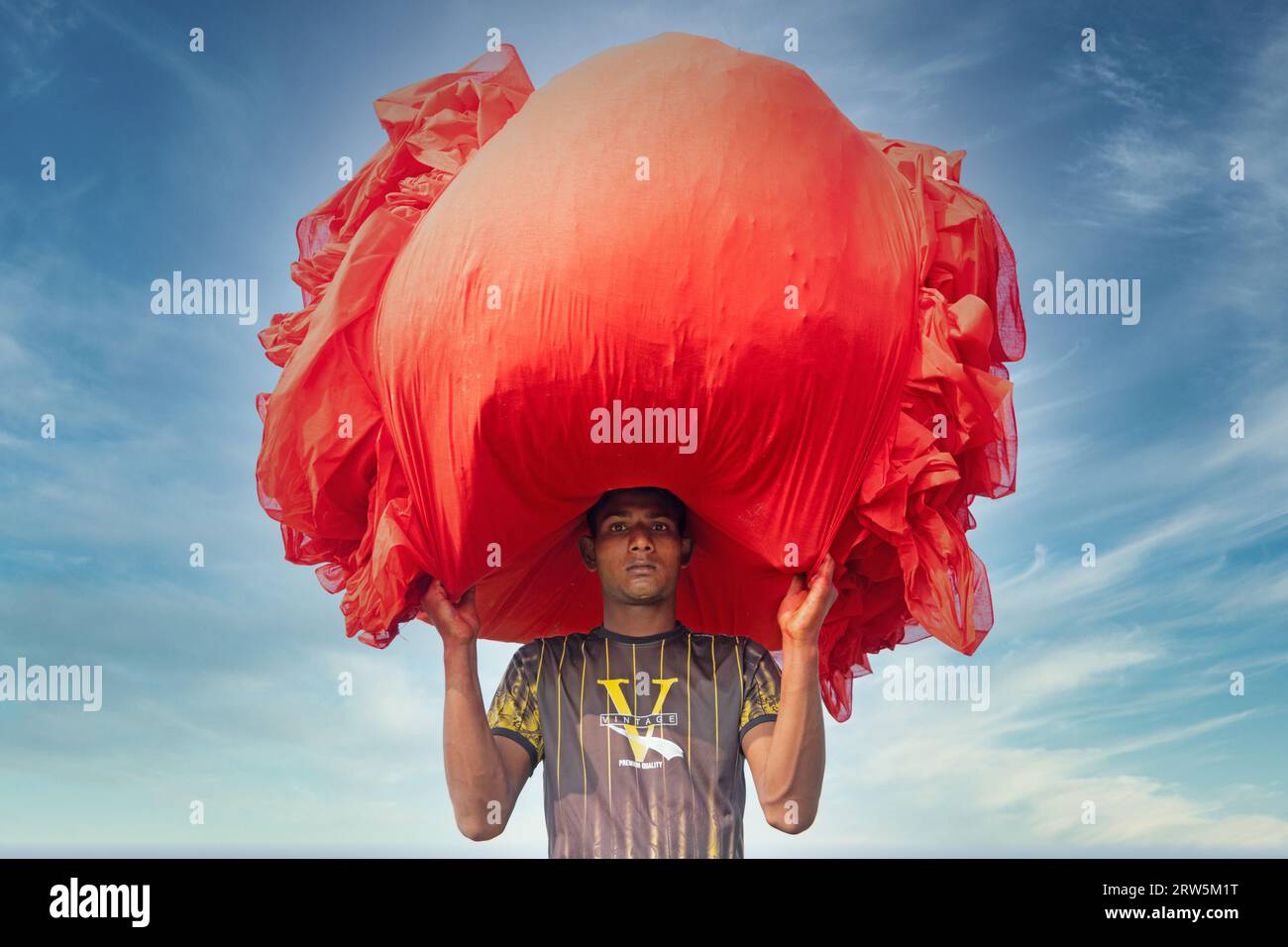 Narsingdi, Bangladesh. 17 septembre 2023. Des centaines de mètres de tissus rouge vif sont disposés en rangées nettes à travers un champ à Narsingdi, au Bangladesh. Connus sous le nom de «Lal Shalu» par les habitants, les longs tissus rouges sont mis à sécher sous le soleil chaud, après avoir été teints avec une couleur rouge vif. L'utilisation de la lumière du soleil pour sécher les tissus réduit les coûts de production car elle est moins chère et plus durable. La méthode de séchage écologique couvre une superficie égale à 5 terrains de football et prend jusqu'à 6 heures à compléter après avoir été placé par les travailleurs au lever du soleil. Crédit : Joy Saha/Alamy Live News Banque D'Images