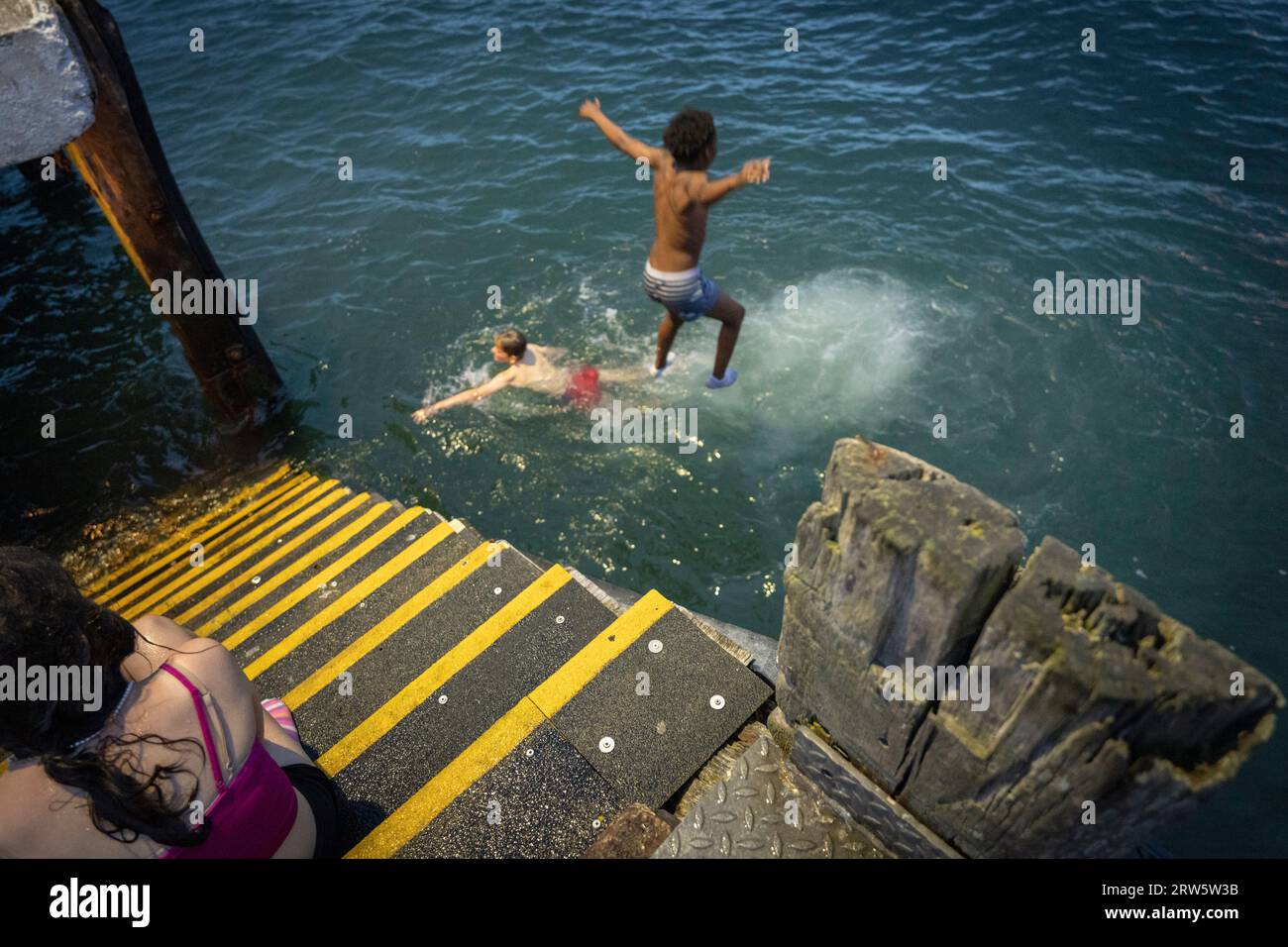 Enfants sautant dans la mer, Cobh, port de Cork, comté de Cork, Irlande, Royaume-Uni Banque D'Images