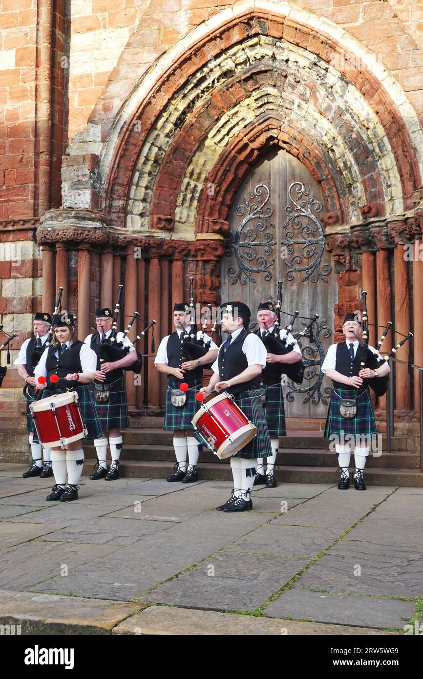 Les membres de la Kirkwall City Pipe Band se produisent devant la façade en grès sculpté et ornée de St. Magnus Cathedral, Kirkwall, Orcades Island Banque D'Images