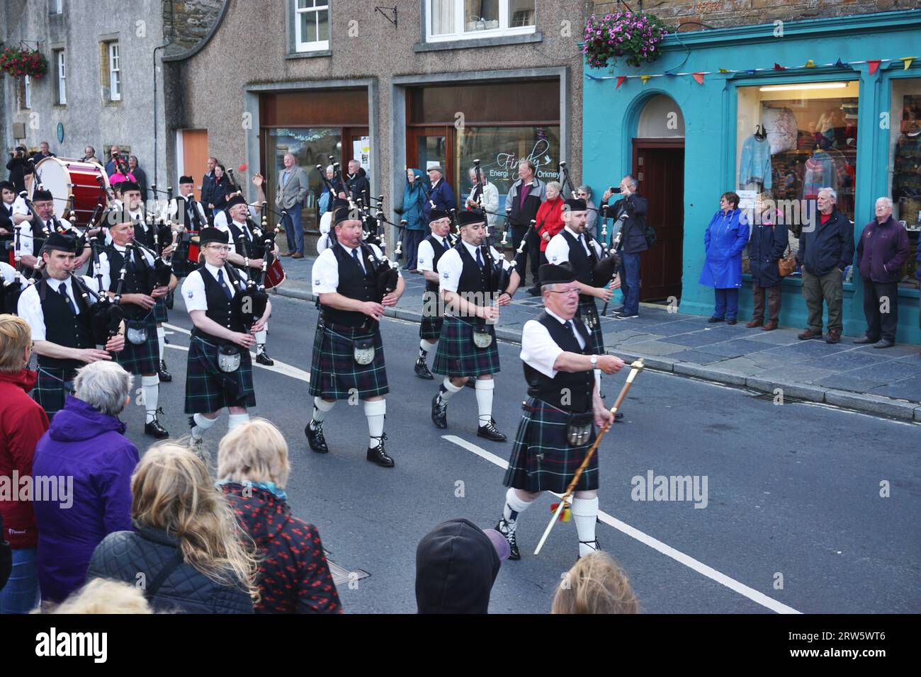 Le tambour majeur porte sa masse à dessus d'or alors qu'il marche devant le Kirkwall City Pipe Band alors qu'ils défilent dans la rue sur l'île des Orcades Banque D'Images