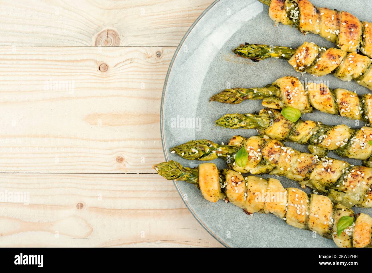 Asperges vertes cuites dans la pâte avec sauce pesto sur une table rustique en bois. Espace de copie. Banque D'Images