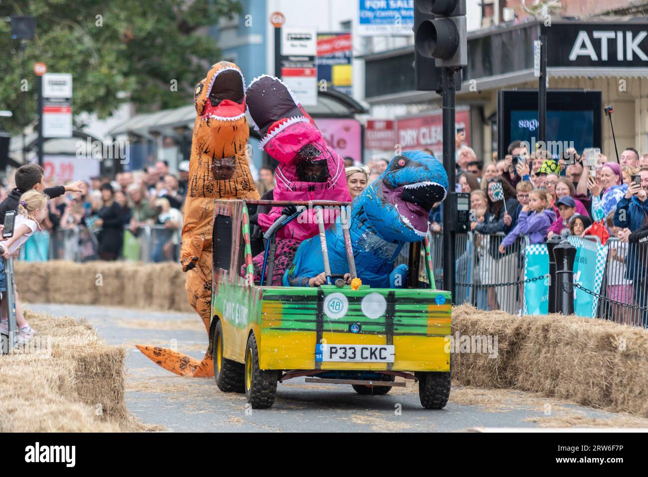 High Street, Colchester, Essex, Royaume-Uni. 17 septembre 2023. La ville historique de Colchester accueille son premier rallye de soapbox, avec environ 50 participants. Les karts sont lancés sur une rampe pour leur donner la vitesse nécessaire pour attaquer le parcours sur la High Street qui comprend divers obstacles avant que les pilotes atteignent la ligne d'arrivée. Équipe nommée Going Extinct portant des costumes de dinosaures Banque D'Images