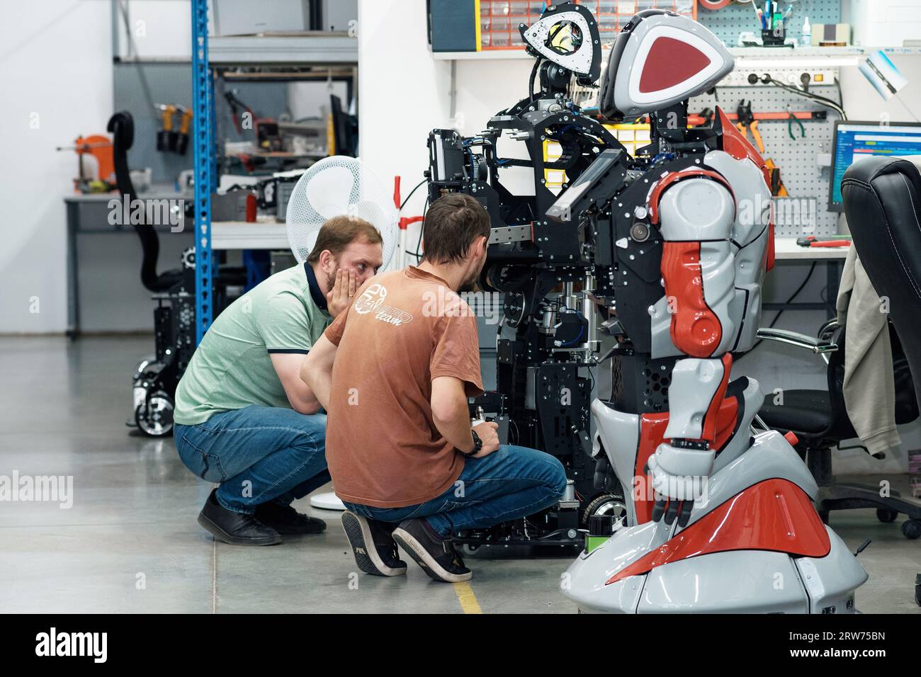 Perm, Russie - 13 juillet 2023 : des ingénieurs en robotique discutent des problèmes de travail dans un atelier d'assemblage de robots Banque D'Images