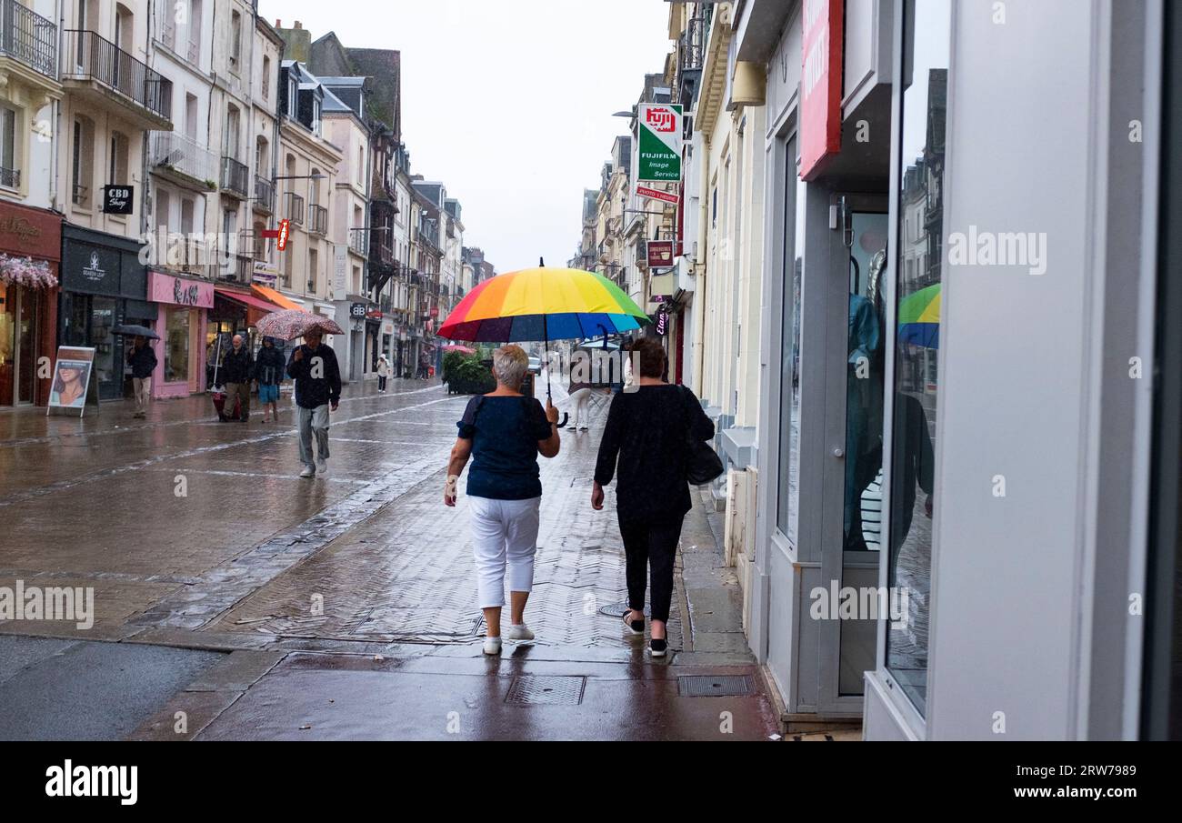 Marcher sous la pluie avec un parapluie arc-en-ciel à travers Dieppe , Normandie Dieppe est un port de pêche sur la côte normande du nord de la France Banque D'Images