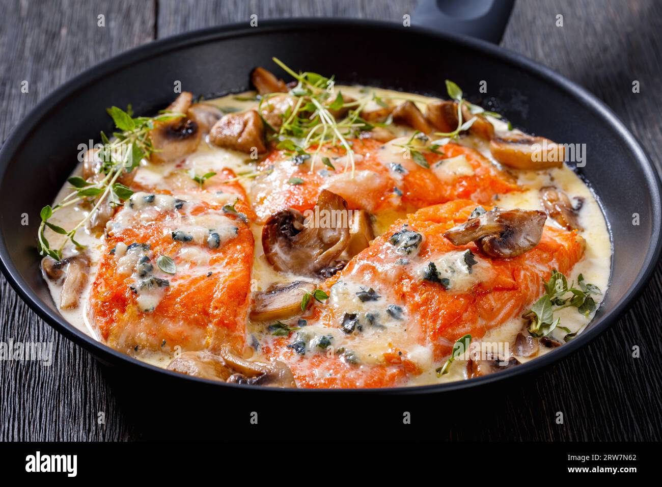 filet de saumon avec sauce crémeuse au fromage de moule bleu et champignons dans une poêle sur une table en bois foncé, gros plan Banque D'Images