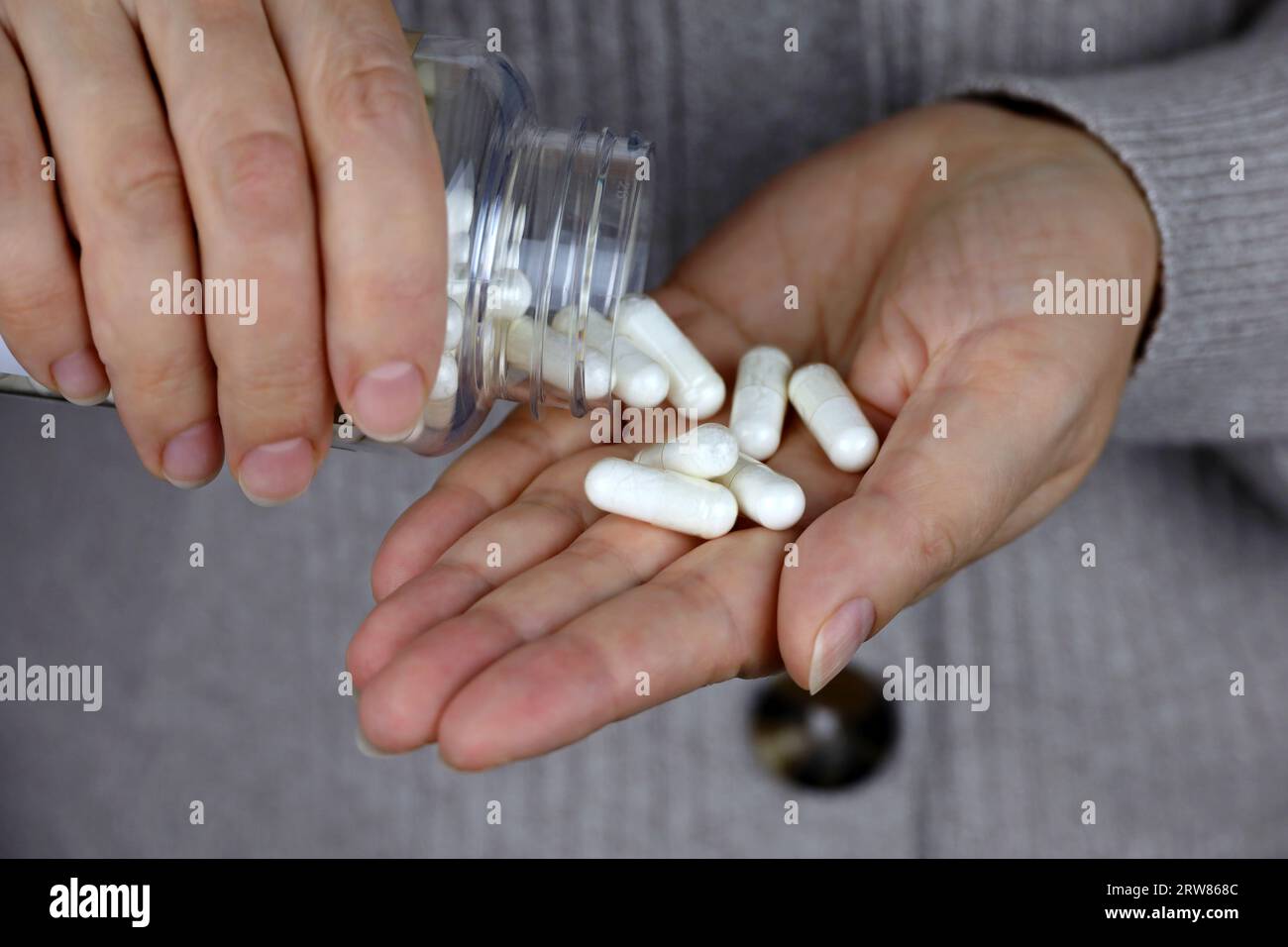 Femme en pull avec des pilules dans les mains. Bouteille avec capsules, concept de vitamines pour la beauté, les soins de la peau, la prise de médicaments Banque D'Images