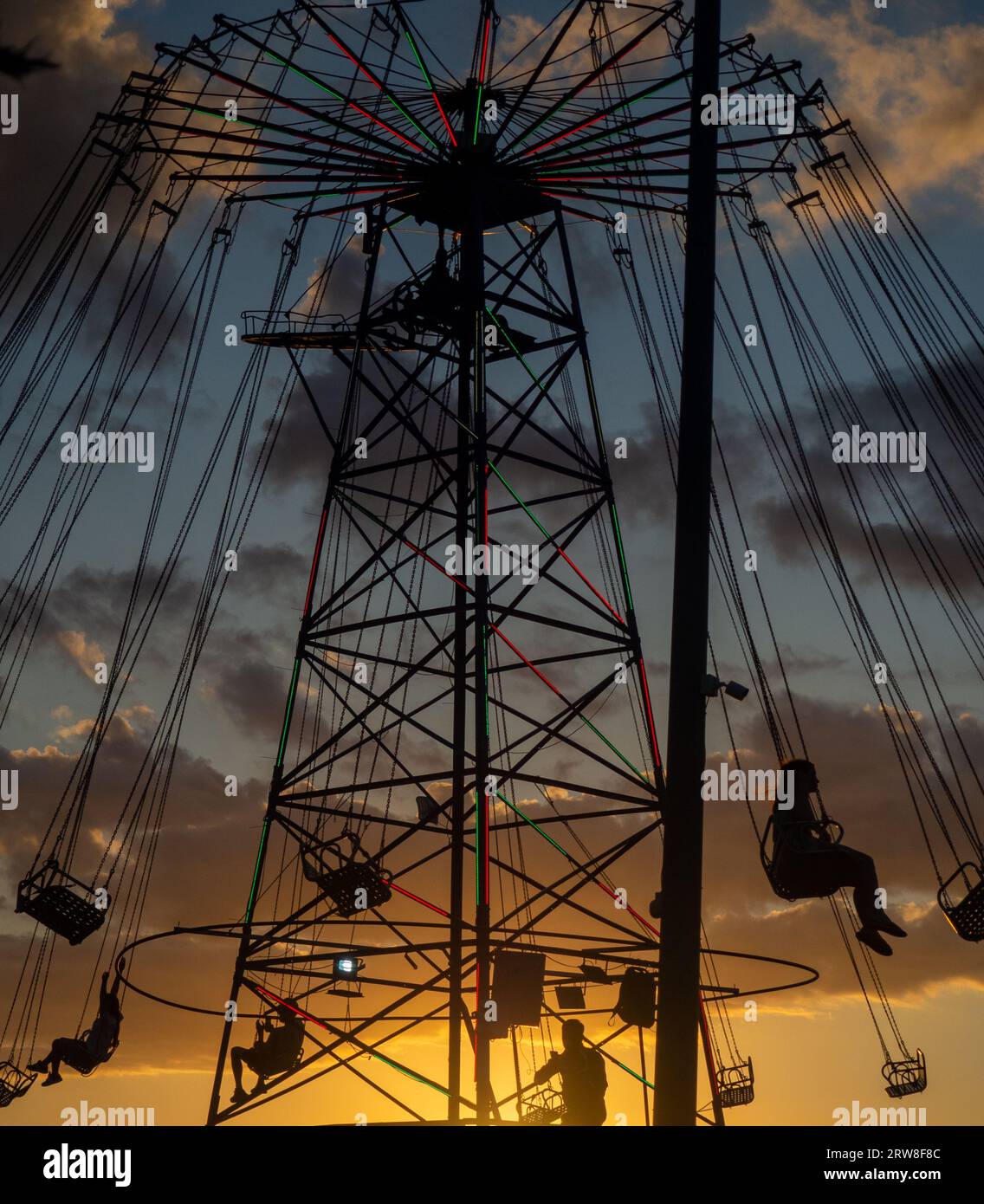 Silhouettes de personnes sur le carrousel. Concept de plaisir et de divertissement. Les gens sur les carrousels au coucher du soleil. Station balnéaire. Lunapark. Adrénaline. Carous de vitesse Banque D'Images