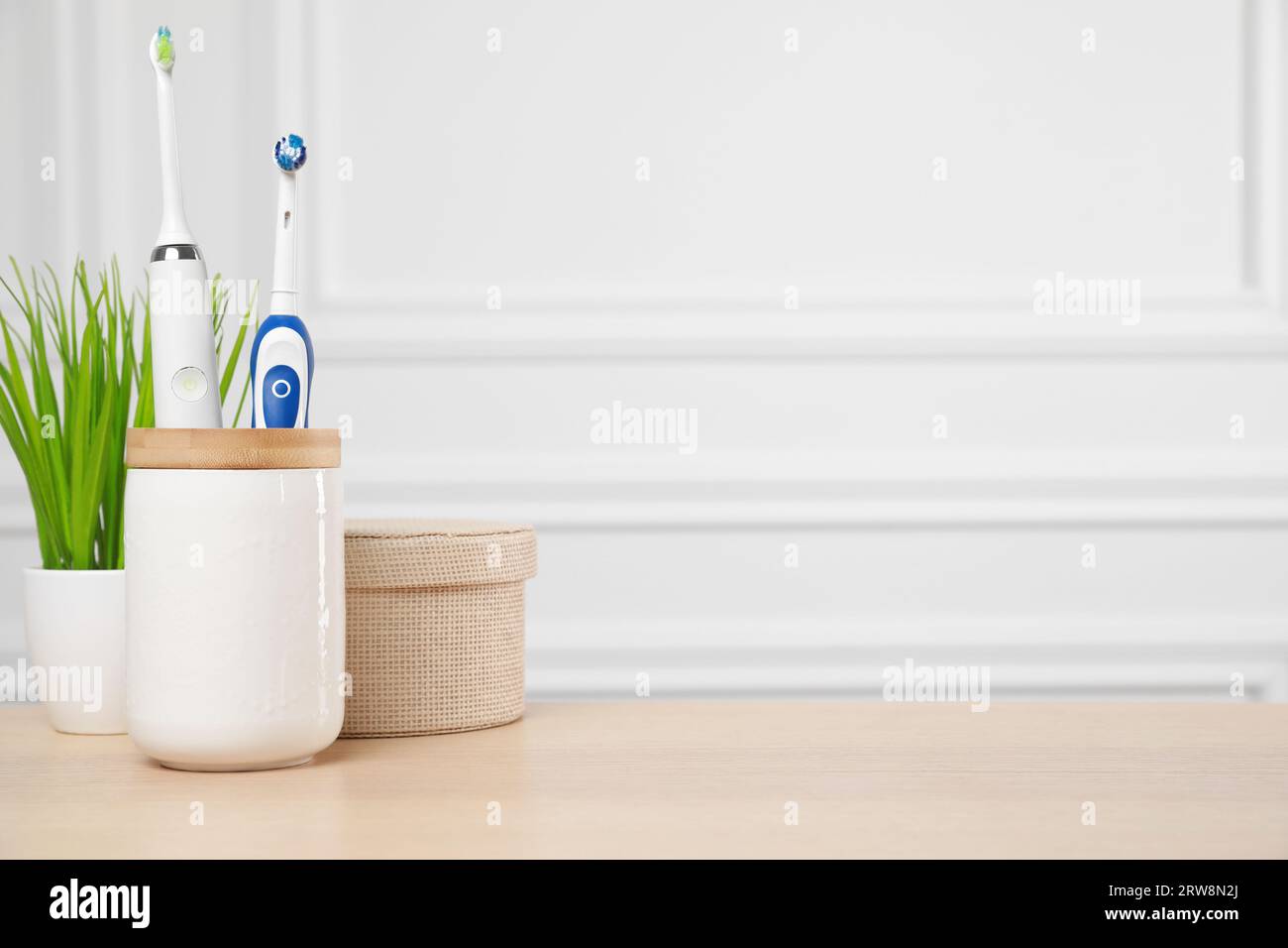 Brosses à dents électriques dans le support sur la table en bois. Espace pour le texte Banque D'Images