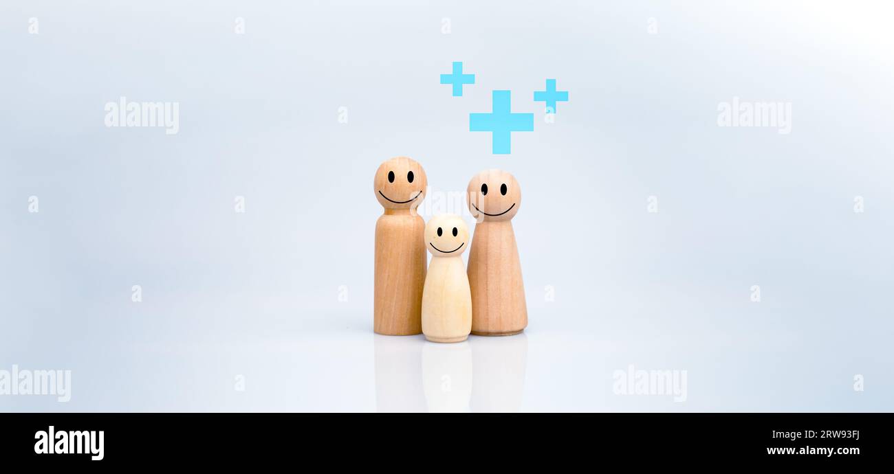 Le concept d'assurance maladie et de bien-être médical. Une famille de poupées en bois avec un signe plus sur fond blanc représente la protection, la réception Banque D'Images