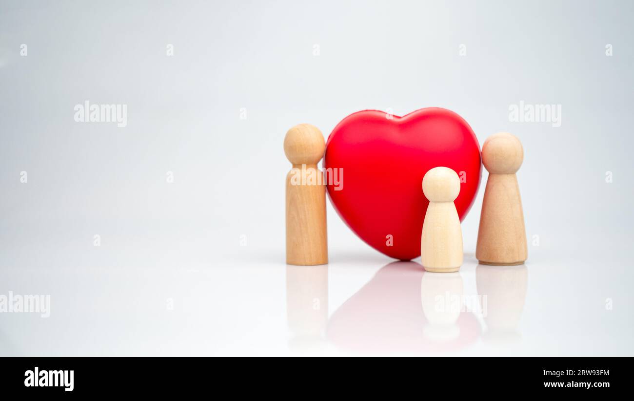 Le concept d'assurance maladie et de bien-être médical. Une poupée en bois avec un coeur rouge sur un fond blanc représente la protection, recevant des avantages. H Banque D'Images