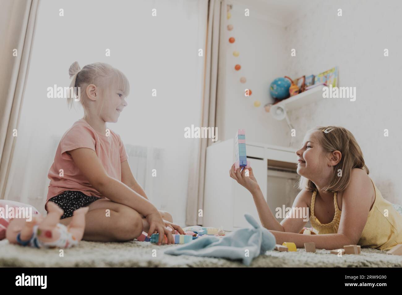 Enfants jouant avec des jouets colorés. Enfants assis sur la moquette dans la chambre à coucher ou la maternelle à la maison, la crèche. Jeu écologique éducatif pour enfant. Interio Banque D'Images