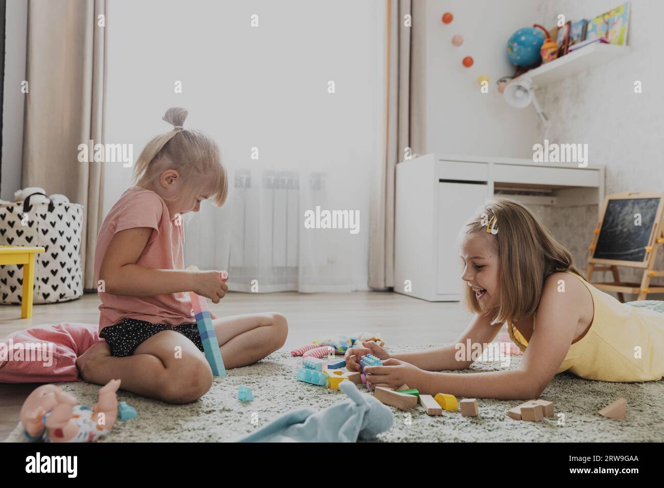Enfants jouant avec des jouets colorés. Enfants assis sur la moquette dans la chambre à coucher ou la maternelle à la maison, la crèche. Jeu écologique éducatif pour enfant. Adorabl Banque D'Images