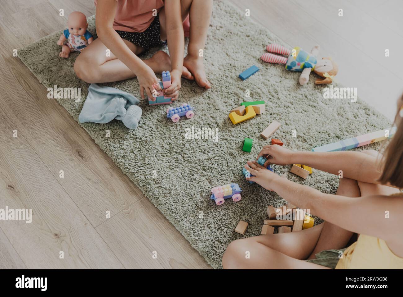 Enfants jouant avec train jouet en bois coloré. Enfants assis sur la moquette à la chambre à coucher à la maison, maternelle, salle de jeux de garderie, aire de jeux, centre de jeux. Jeu amusant et écologique éducatif pour enfant Banque D'Images