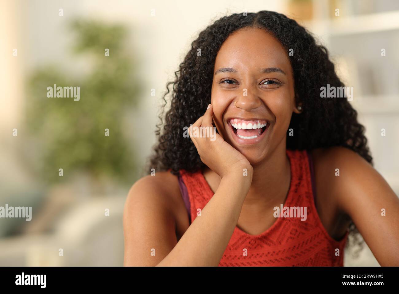 Portrait en vue de face d'une femme noire riant à la caméra avec des dents blanches à la maison Banque D'Images