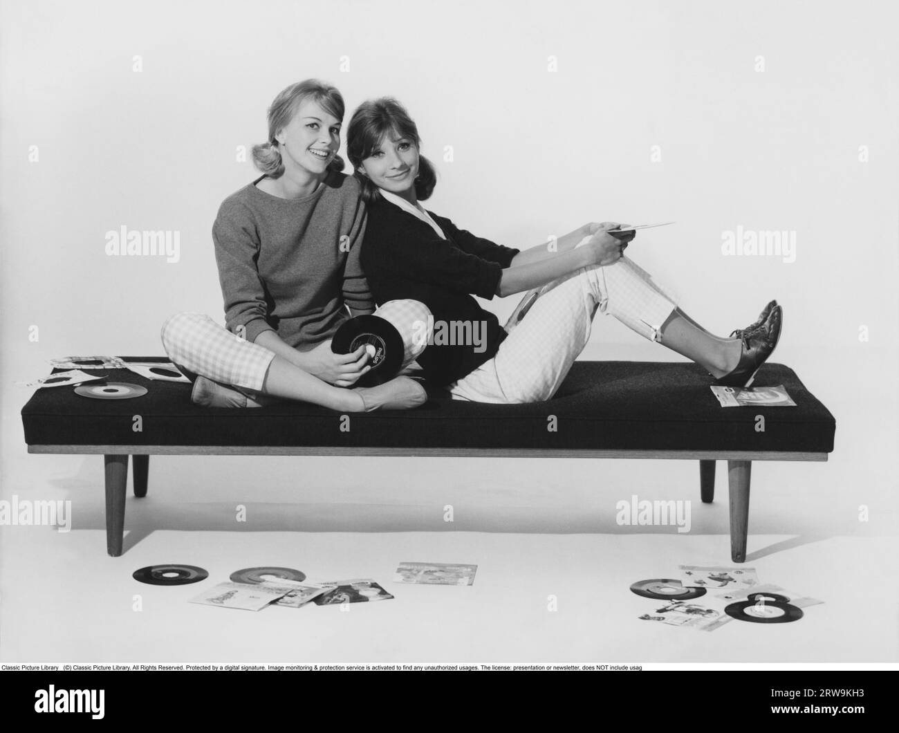 style de vie des années 1960. Deux filles dans des vêtements typiques des années 1960 sont assis ensemble tenant des disques de musique. Suède 1960 Banque D'Images