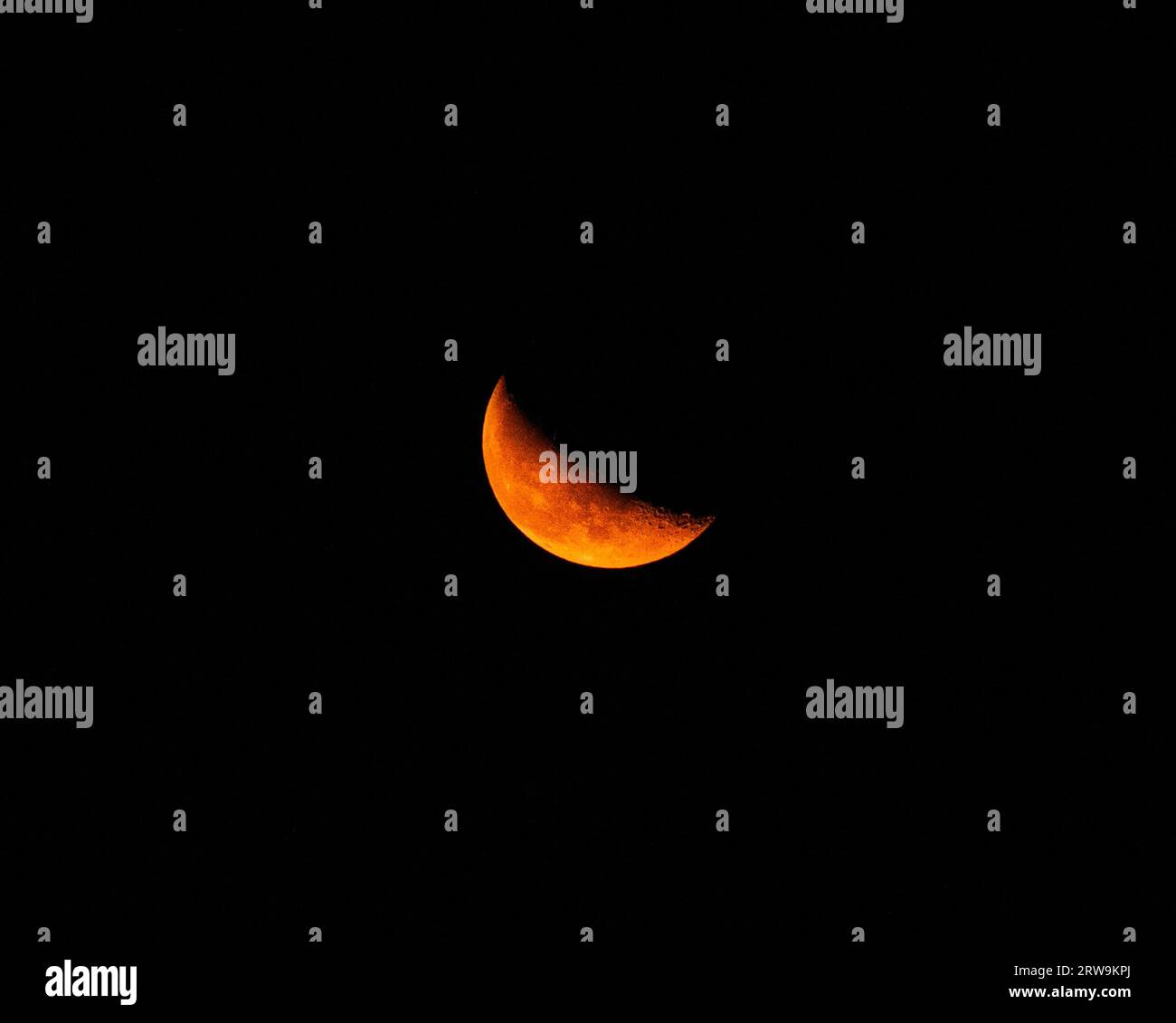 Une vue pittoresque d'un croissant de lune orange brillant posé contre un ciel nocturne Banque D'Images