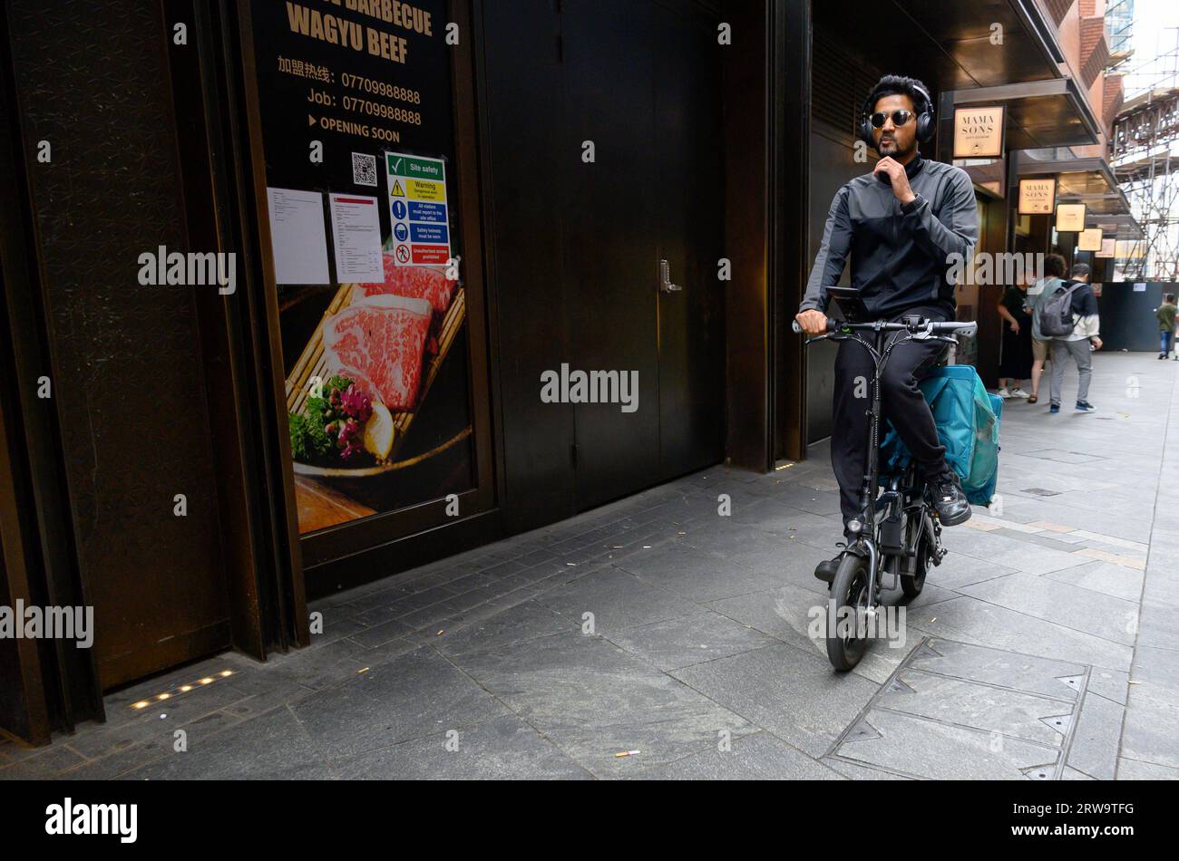 Londres, Royaume-Uni. Chauffeur livreur à bord d'un e-scooter dans Chinatown Banque D'Images