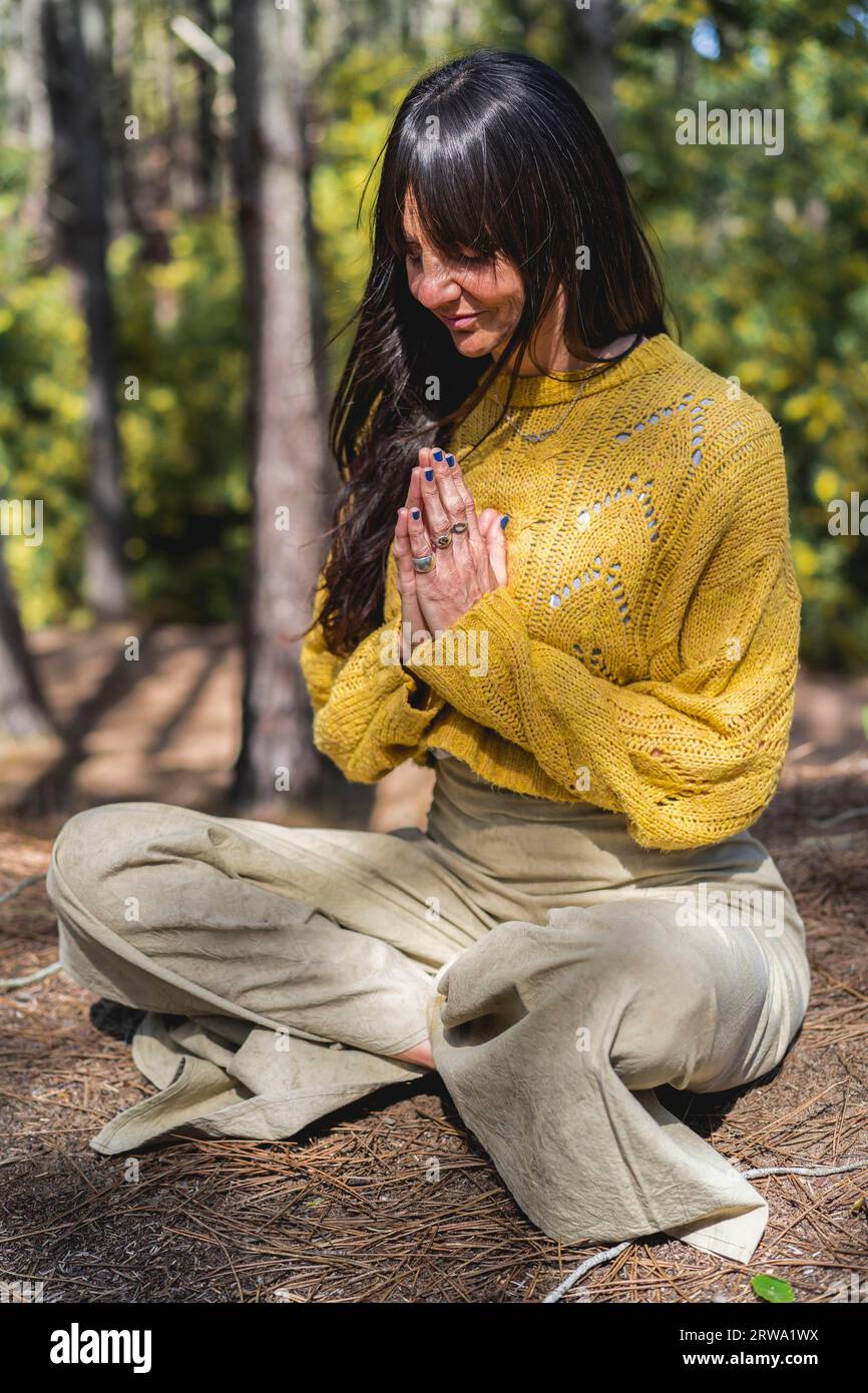 Femme médite avec les mains serrées sur les bois. Tir vertical Banque D'Images