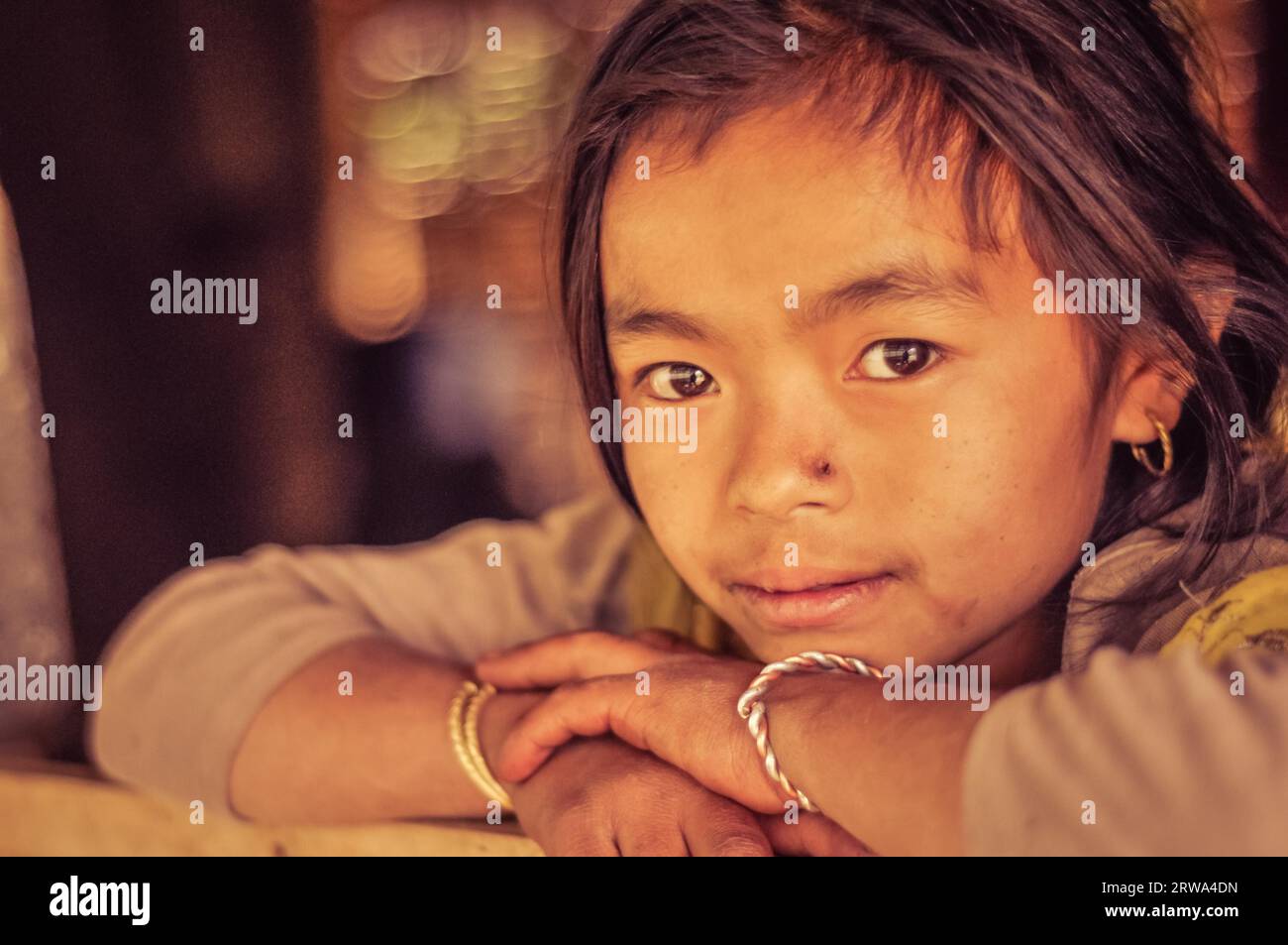 Kanchenjunga Trek, Népal, vers avril 2012 : jeune fille aux yeux bruns et petite cicatrice sur le nez avec la tête sur les mains à Kanchenjunga Trek, Népal. Banque D'Images