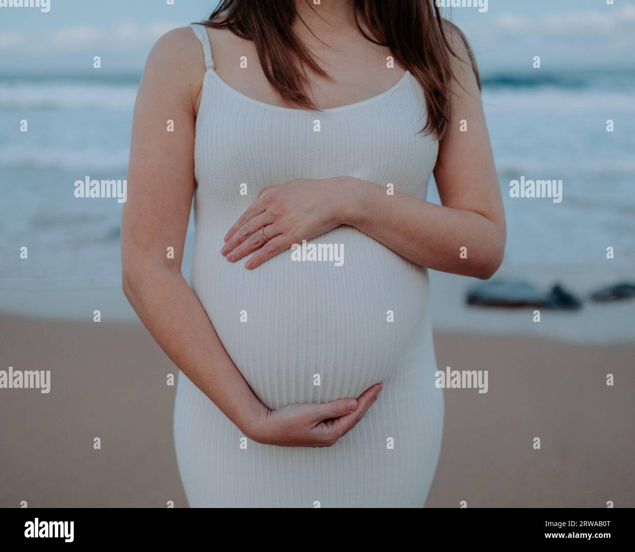 Portrait de la mère enceinte au troisième trimestre à la plage à coucher de soleil Banque D'Images